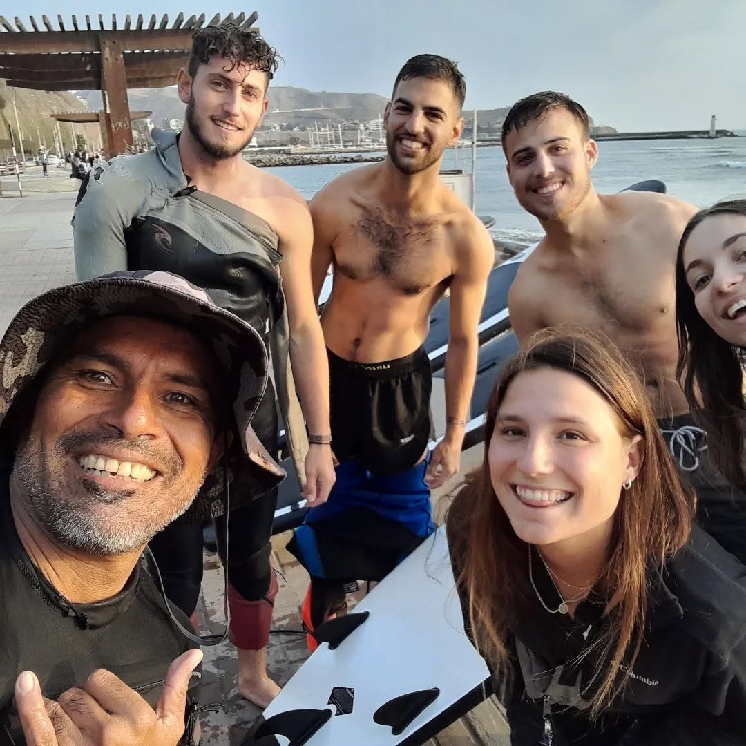Richard and a smiling group of surfers together beside the ocean in Lima